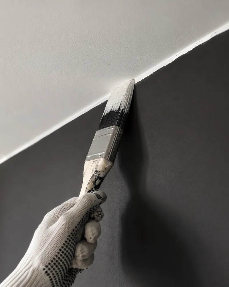Brush cutting a crisp edge where the ceiling meets a charcoal wall
