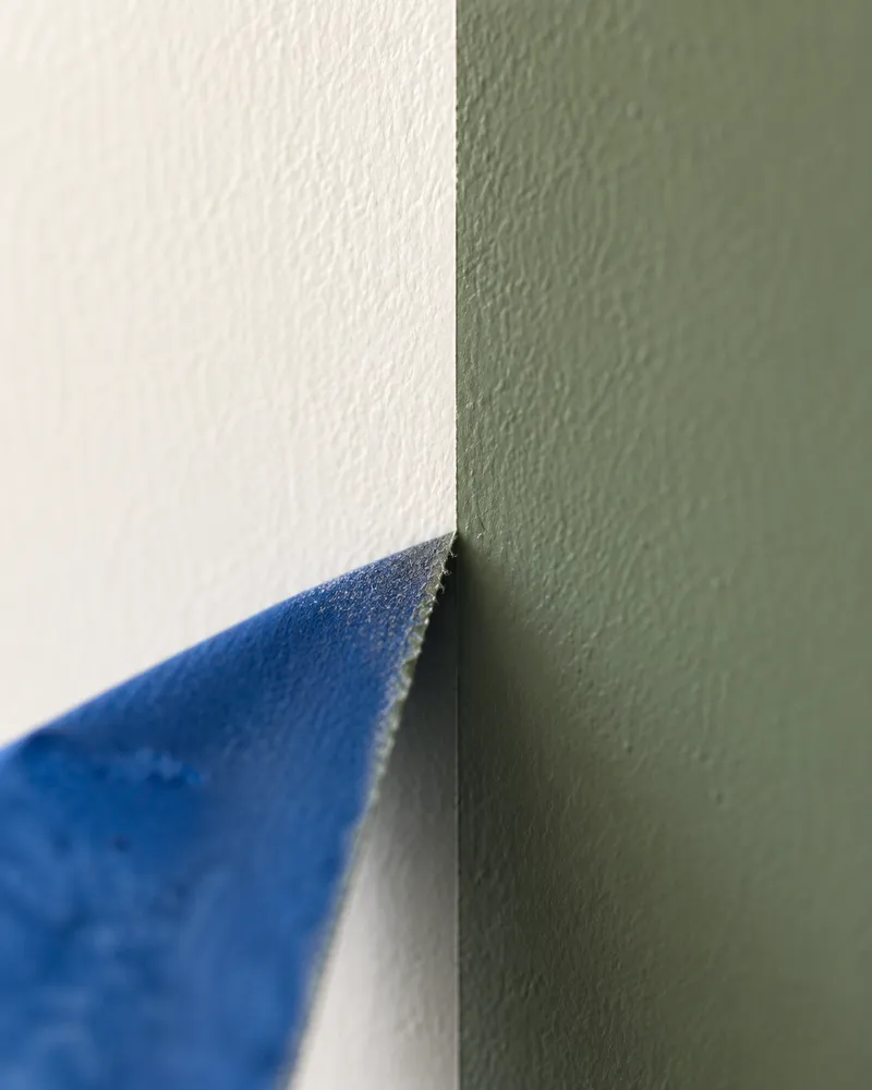 Painter’s tape peeling away to reveal a razor-sharp line between white and sage green